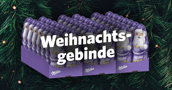 Milka Weihnachtsmänner im Displaykarton vor Tannenzweigen – Aufschrift ‚Weihnachtsgebinde