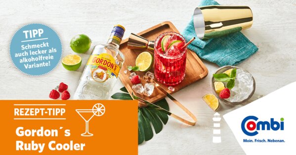 Weißer Tisch mit Limetten, Himbeeren, Cocktail-Mixer, Cocktail und einer Flasche Gordon´s Gin