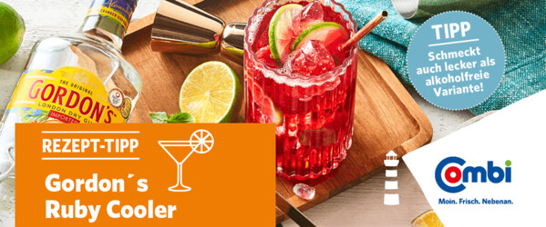 Weißer Tisch mit Limetten, Himbeeren, Cocktail-Mixer, Cocktail und einer Flasche Gordon´s Gin