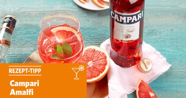 Blauer Tisch mit einem Cocktail, einer halben Blutorange und einer Flasche Campari