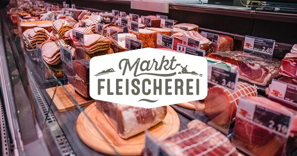 Bedientheke mit einer großen Auswahl an frischem Fleisch und Wurstwaren in der Markt-Fleischerei, beschriftet mit Preisen und liebevoll angerichtet.