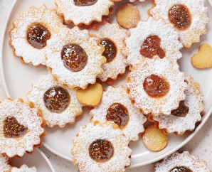 Feine Spitzbuben-Kekse mit Puderzucker und fruchtiger Feigenmarmelade auf einem weißen Teller