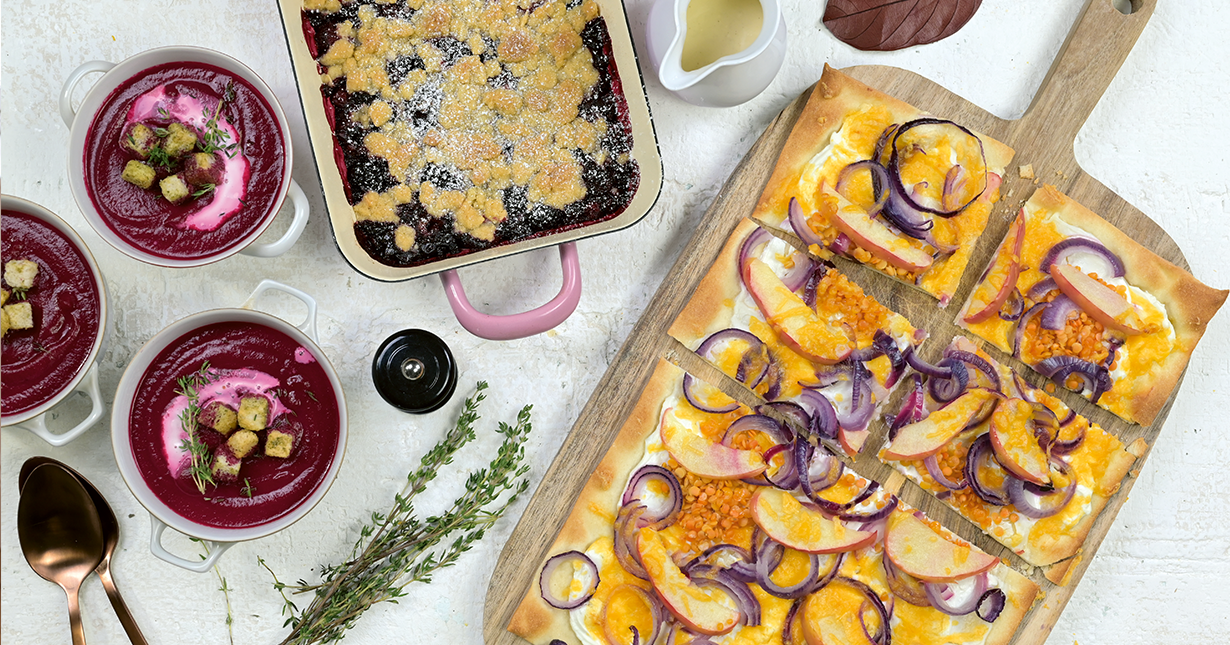 Herbstliches Friendsgiving-Menü mit Rote-Bete-Suppe, knusprigem Flammkuchen und Beeren-Crumble auf einem rustikalen Tisch