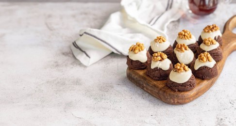 Schokoladige Kakao-Hügel mit weißer Glasur und halben Walnüssen auf einem Holzbrett serviert