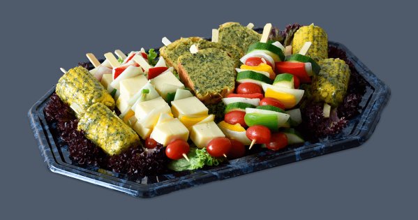 Maiskolben und Gemüsespieße mit Salat auf einer Platte dekoriert