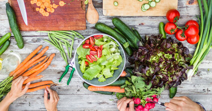 Tisch mit einen Schneidebrett wo Gemüse geschnitten wird